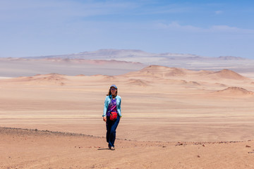 Fototapeta na wymiar A woman walks through the Paracas desert, Peru.