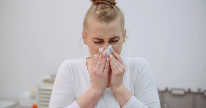 sneezing woman has coronavirus symptoms