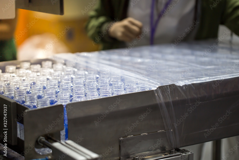 Poster Production line packing empty plastic bottles in plastic bag