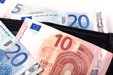 Simple pile of european currency - euro banknotes, 10, 20, 5 bills laying on a black stylish wallet. Pocket money, small bills closeup Abstract business payment and little investment financial concept