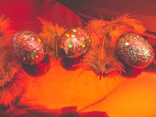 Red gold coloured easter eggs, lying down on a red surface with a blurred reflection