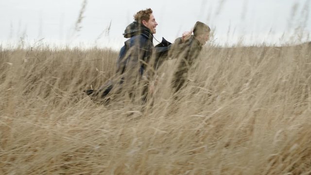 Two Friends Running Across The Field. They Bounce And Catch Up With Each Other.