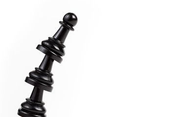 Simple leaning tower made of chess pawn pieces, curved bent construct of black game pieces placed...