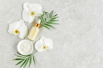 Essential oil, vegetable extract, serum,  hyaluronic acid, facial cream, tropic palm leaves on gray marble background. Spa skincare concept.  Natural/Organic spa cosmetics products. Flat lay, top view