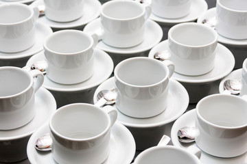 Many empty white tea cups abstract food industry background texture, repetitive pattern Cups stacked with spoons wallpaper White dishes, catering and food service banquet preparations abstract concept