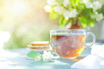 Glass cup of herbal tea, jasmine tea and jasmine flowers on an old wooden table with a blurred green natural background. The concept of tea, retro style. soft selective focus