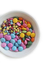 Chocolate candies with coloful glazes in a white bowl isolated on white background