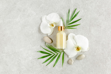 Bottle with hyaluronic acid / essential oil, tropic palm leaves on gray marble background. Concept of modern beauty. Natural / Organic cosmetics products. Flat lay, top view.
