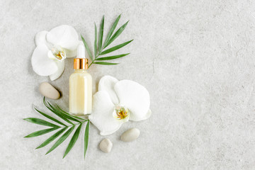 Naklejka na ściany i meble Bottle with hyaluronic acid / essential oil, tropic palm leaves on gray marble background. Concept of modern beauty. Natural / Organic cosmetics products. Flat lay, top view.