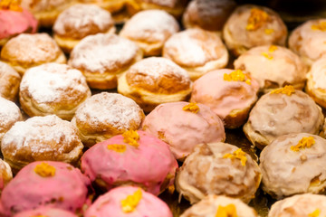 Lots of sweet tasty donuts without a hole, warm background texture pattern. Group of delicious traditional european doughnuts at the bakery fresh from the oven Pink and white, powdered sugar, frosting