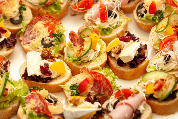 Lots of simple tasty small little mini sandwiches, gourmet smorgasbord closeup, food photography macro. Healthy delicious treats on bread with cheese, vegetables. Banquet cuisine, quick snack concept