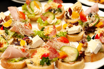 Easy to make many tasty little mini sandwiches, small gourmet smorgasbord closeup, food photo macro. Healthy delicious treats on bread with cheese, vegetables and meat. Banquet cuisine, snack concept