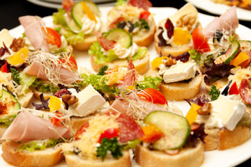 Easy to make many tasty little mini sandwiches, small gourmet smorgasbord closeup, food photo macro. Healthy delicious treats on bread with cheese, vegetables and meat. Banquet cuisine, snack concept