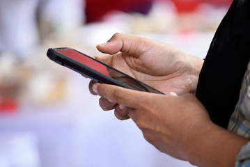 Hand holding handphone - people play handphone with blur background