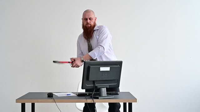 Stressed crazy businessman smashing his computer in office using ax problem concept. The man has problems at work and frustration.