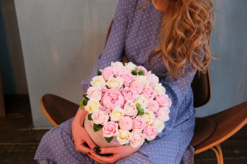 a girl in a blue dress and white sneakers is sitting with a bouquet of roses