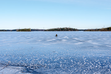 Fisherman on underwater fishing on frozen lake Saimaa, Finland