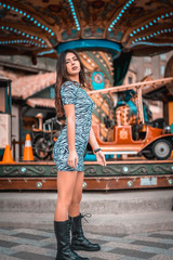Fototapeta na wymiar Street style, caucasian brunette with long hair on a carousel at the fair with short skirt