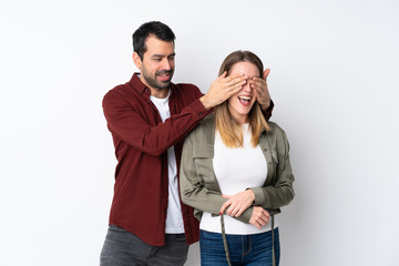 Couple in Valentine Day over isolated background covering his eyes to surprise him