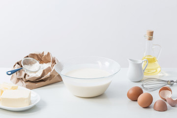 Fototapeta na wymiar dough in glass plate and products for its preparation on white