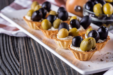 delicious snack tartlets on rustic wooden background