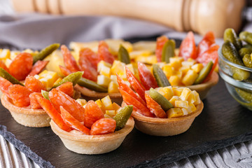 delicious snack tartlets on rustic wooden background
