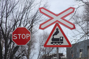 Road signs STOP and train near single track railway crossing
