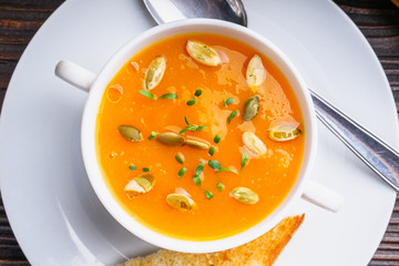 pumpkin cream soup on rustic wooden background