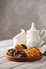 Set of different cookies in a plate and tea on a wooden background.
