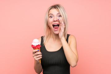 Young blonde woman with a cornet ice cream over isolated pink background shouting with mouth wide open