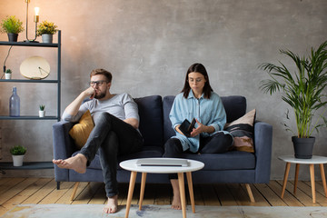 Young Couple Sitting on the Sofa. The Woman Tears Up The Photo. Family Conflict.