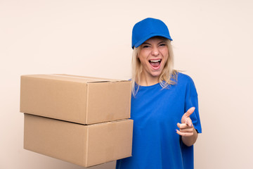 Young delivery woman over isolated background points finger at you