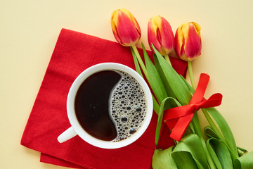 Bouquet of red tulips with black coffee on a light background