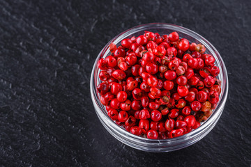 pink peppercorns on a dark stone background