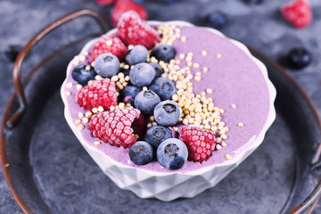 Fruit smoothie bowl with yogurt decorated with healthy raspberry, blueberry and puffed quinoa grain...