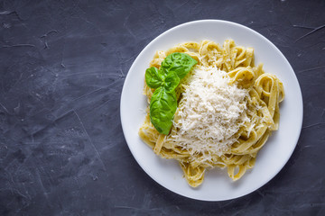 Delicious tagliatelle pasta with pesnto sauce on dark stone background