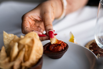 An Asian woman tasting tortilla Nacho maxican chips and chilli sauce during the lunch in a restaurant close to nature in BALI
