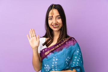 Fototapeta na wymiar Young Indian woman isolated on purple background saluting with hand with happy expression