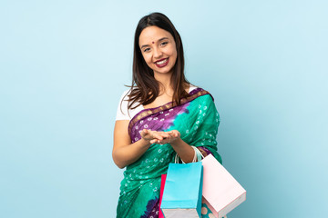 Young Indian woman with shopping bags holding copyspace imaginary on the palm to insert an ad