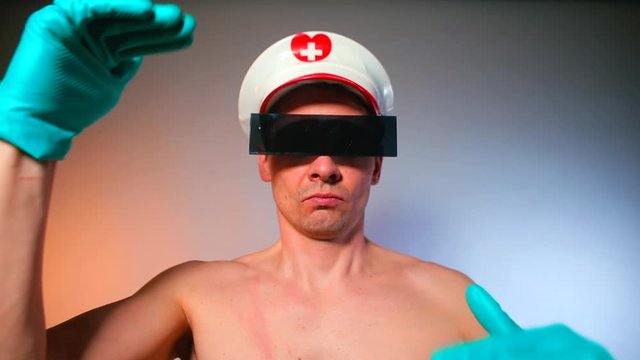 A man in glasses and a bang-cap is doing dance movements with gloved hands. Kinky party concept.