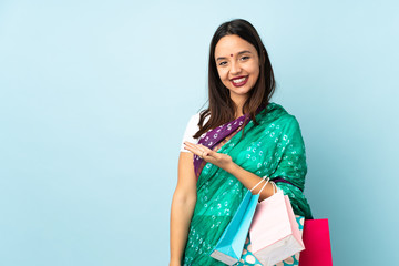 Young Indian woman with shopping bags presenting an idea while looking smiling towards