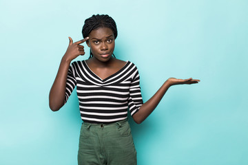 Afro young woman with finger on head with open palm ask to think isolated on blue background