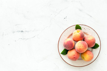 Summer fruits. Ripe red peaches on plate on white table top-down copy space