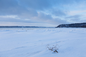 View of the Cap-Rouge bay beach covered in pristine fresh snow with pretty clouds in the sky during a winter blue hour early morning, Quebec City, Quebec, Canada