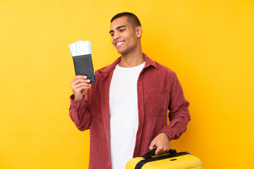 Young African American man over isolated yellow background in vacation with suitcase and passport