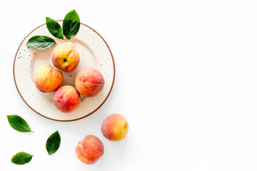 Summer fruits. Ripe red peaches on plate on white table top-down copy space