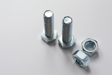 two bolts and nuts lying with them. White background.