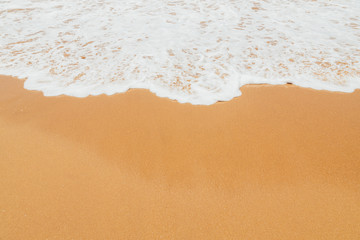 Foam of the ocean surf waves on beach sand.