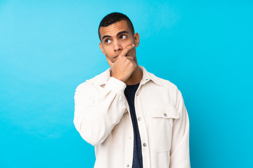 Young African American man over isolated blue background having doubts and with confuse face expression