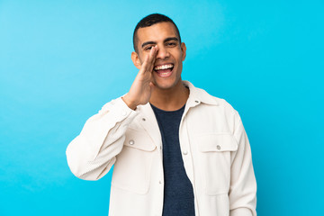 Young African American man over isolated blue background shouting with mouth wide open